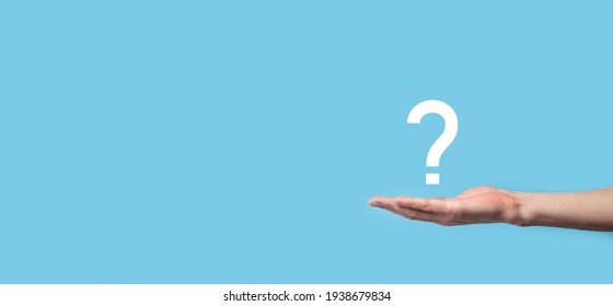 Male Hand Holding Question Mark Icon On Blue Background.Banner With Copy Space. Place For Text