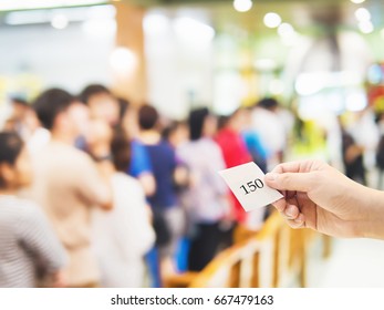 Male Hand Holding Queue Card Over Long Line Waiting People