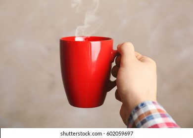 Male Hand Holding Red Cup On Blurred Background