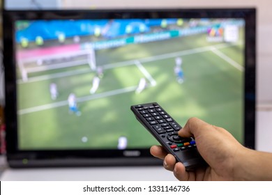 Male hand holding a remote control while watching LCD TV in living room. - Powered by Shutterstock