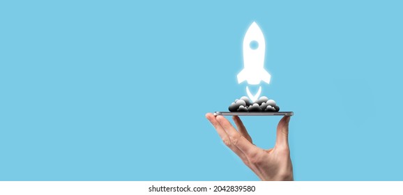 Male hand holding rocket icon that takes off, launch on blue background. rocket is launching and flying out, Business start up, Icon marketing on modern virtual interface.Start up concept