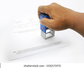 A Male Hand Holding A Self-inking, Rubber Company Logo Stamp. A Paperwork. Office Accessories.