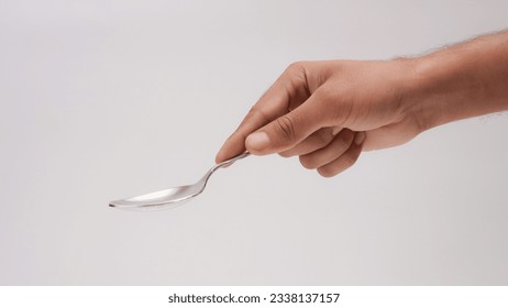 Male Hand Holding A Silver Stainless Spoon Closeup Photo Isolated On Grey Background