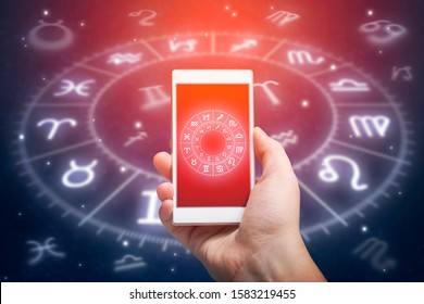 Male hand holding smart phone device with astrology app, close up. Astrology and horoscope reading concept.