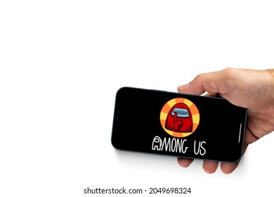 Male hand holding a smartphone with Among Us mobile game app on the screen. White background. Rio de Janeiro, RJ, Brazil. September 2021.