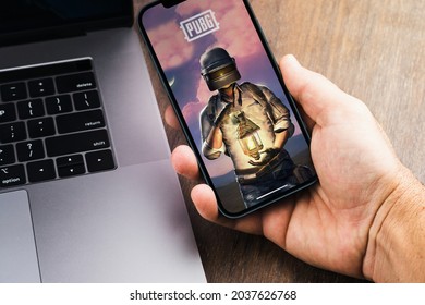 Male hand holding a smartphone with Player's Unknown Battleground, PUBG online shooting gaming mobile game app on the screen. Wooden Background. Rio de Janeiro, RJ, Brazil. August 2021.