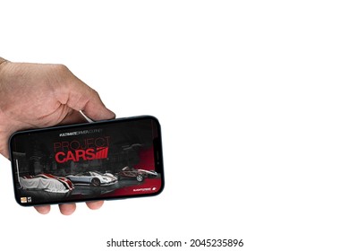 Male hand holding a smartphone with Project Cars Go mobile game app on the screen. White background. Rio de Janeiro, RJ, Brazil. September 2021.