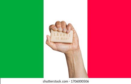 Male Hand Holding Soap With Words: Wash Your Hands Written In Italian Language With Flag Of Italy As Background