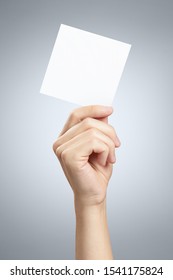 Male hand holding a square blank sheet of paper (ticket, flyer, invitation, coupon, etc.) on gray background