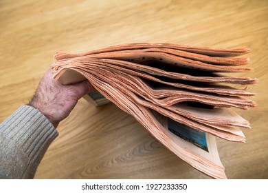 Male Hand Holding Stack Of Generic Business Newspaper Defocused Blur Background