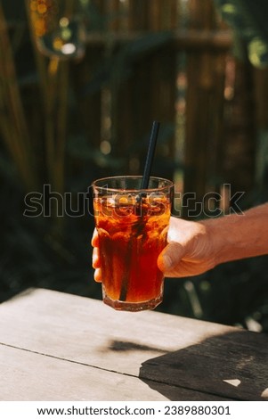 Male hand holding stack with tea and ice on sunlight background