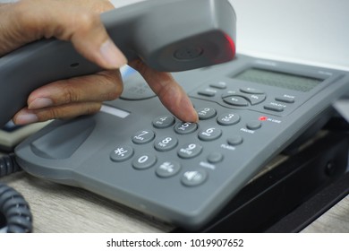 Male Hand Holding Telephone And Dailing A Phone Number.