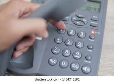 Male Hand Holding Telephone And Dailing A Phone Number.