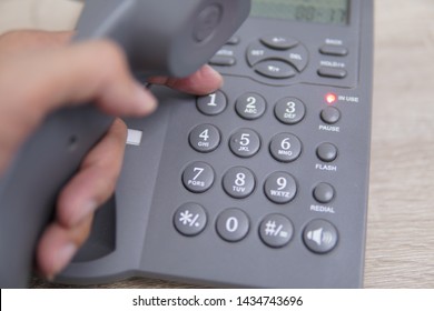 Male Hand Holding Telephone And Dailing A Phone Number.