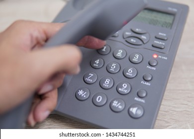 Male Hand Holding Telephone And Dailing A Phone Number.