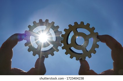 Male hand holding three wooden cog gear wheel on sunny sky background. sunshine and blue sky . sun rays.one part of whole. symbol of association and connection. business strategy