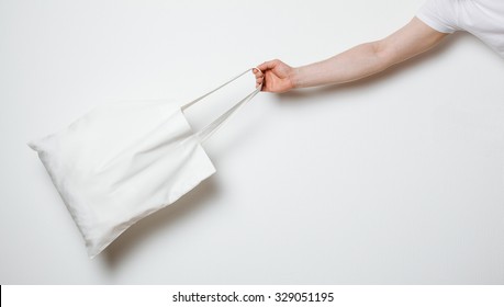 Male Hand Holding White Textile Bag, Neutral Background