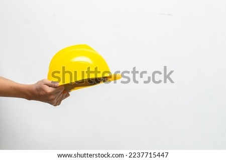 Male hand holding yellow safey hard hat isolated over white background. work safety concept. labour day concept