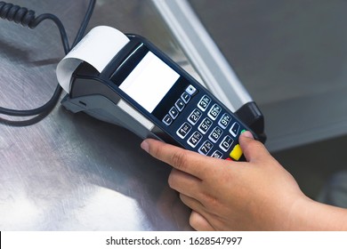 Male hand holds a bank terminal in hands at the cash desk, enters a password from a credit card. The check goes out and the cash register