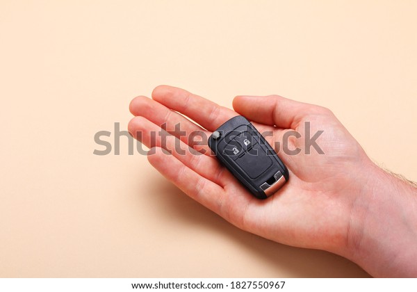 Male hand holds car keys on beige background.\
Concept car, car rental, gift, driving lessons, driving license.\
Flat lay, top view