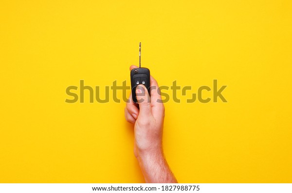 Male hand holds car keys on yellow background.\
Concept car, car rental, gift, driving lessons, driving license.\
Flat lay, top view