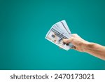 Male hand holds cash for financial income or online service isolated on a green background. Arm holding a lot of money,  big profit.