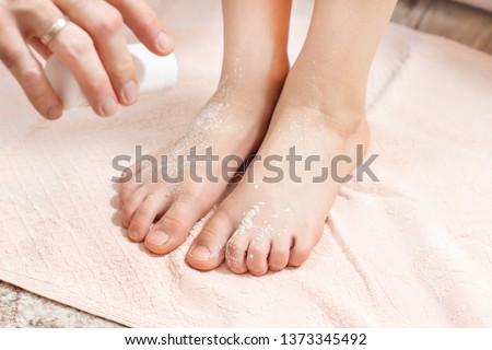 The male hand holds the container with the powder and pour the white powder on child's feet. Medicine against sweating of the feet.