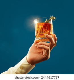 Male hand holds glass of whiskey, rum shining in light decorated with slice of citrus and rosemary against blue background. Concept of alcohol, drink, party, degustation, holiday. Copy space for ad - Powered by Shutterstock