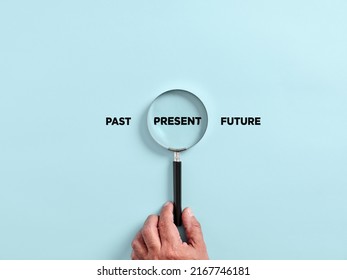 Male hand holds a magnifier focusing on the present time alongside the past and future. To focus on the current situation, positive thinking mindset concept.