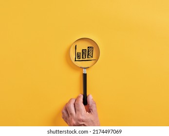 Male hand holds a magnifier focusing on a rising or increasing graph. Financial economic growth and business profitability concept. - Powered by Shutterstock