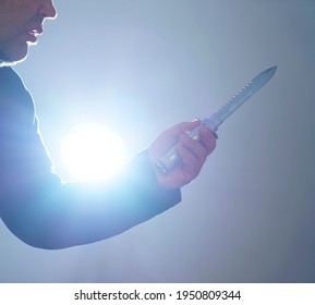 Male Hand Holds Military Knife Isolated On Blue  Background. Backlit. 