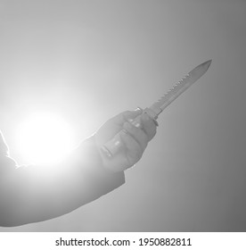 Male Hand Holds Military Knife Isolated On Blue  Background. Backlit. 