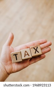 Male Hand Holds The Word TAX Return From Wooden Letters. National Tax Day In The United States. Federal Deadline For Taxation. Tax Day Close-up