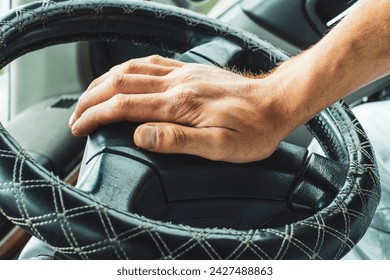 Male hand honking the car horn, man driving vehicle and beeping, front and back background blurred