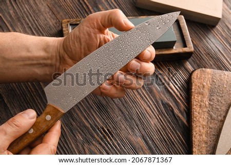 Male hand with knife on wooden background, closeup