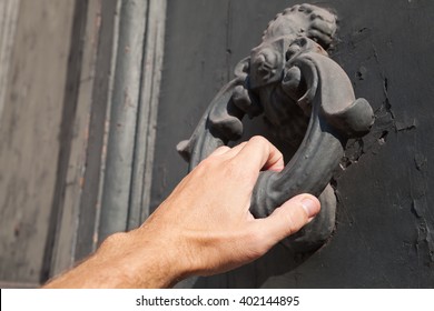 Male Hand Knocking Old Black Door With Metal Ring Knocker