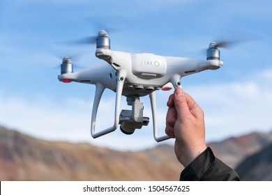 Male hand launches / catches professional drone quad copter DJI Phantom 4 Pro with digital camera 4K on background of rocky mountains. Kamchatka Peninsula, Russian Far East at September 12, 2019