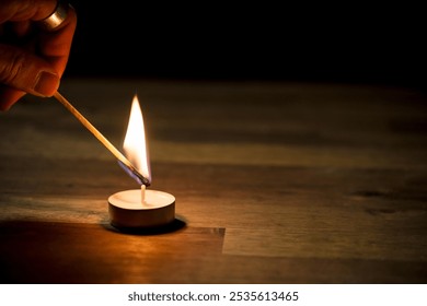 Male hand lighting a small white tea candle on a wooden table, close up shot. Tealight ambiance concept. - Powered by Shutterstock