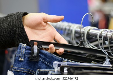 Male Hand Looking Through Pants On A Clothing Rack In Store