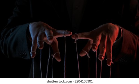 Male hand with marionette strings on black isolated backgorund. Boss in a black business suit controlling managers. Concept of dictatorship and control of the government of the people. Close up. - Shutterstock ID 2204103301