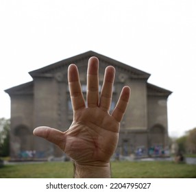 Male Hand On Blurred Big House Background. Open Human Palm With Long Fingers. Real Estate. Prediction Of Fate Along The Lines Of The Palm - Palmistry. 