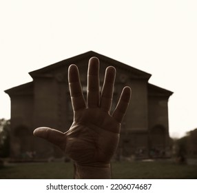 Male Hand On Blurred Big House Background. Open Human Palm With Long Fingers. Real Estate. Prediction Of Fate Along The Lines Of The Palm - Palmistry. 