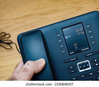 Male Hand On Phone With Message: Please Connect Mobile Base Text On The New Office Telephone With Large Digital Display With DECT1 Base Name And Current Date