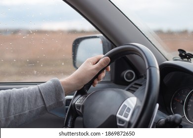 Male hand on the steering wheel of a Mitsubishi car. Autumn rain outside the window. Comfortable SUV driving.