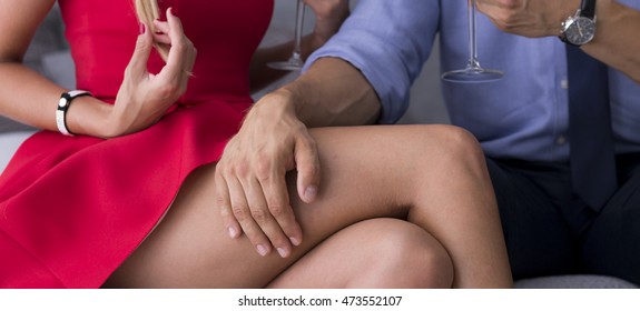 Male Hand On Thigh Of Woman In A Red Dress At An Intimate Meeting