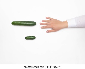 Male hand on a white background reaching for a big cucumber, the concept of increasing the male penis using different techniques, medical, copy space, erection