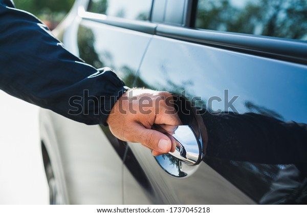 Male\
hand open the car door pulling the handle of a\
car.