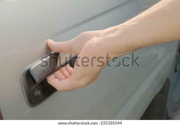 Male hand opening car door from outside by pulling\
black plastic door handle