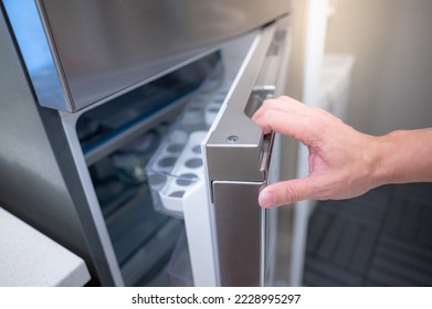 Male hand opening fridge or refrigerator door in kitchen showroom. Buying appliance for home interior design. - Shutterstock ID 2228995297