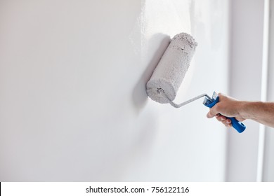 Male hand painting wall with paint roller. Painting apartment, renovating with white color paint - Shutterstock ID 756122116